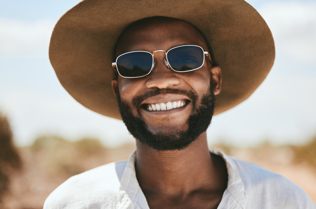 Editorial photo of smiling model wearing hat and sunglasses